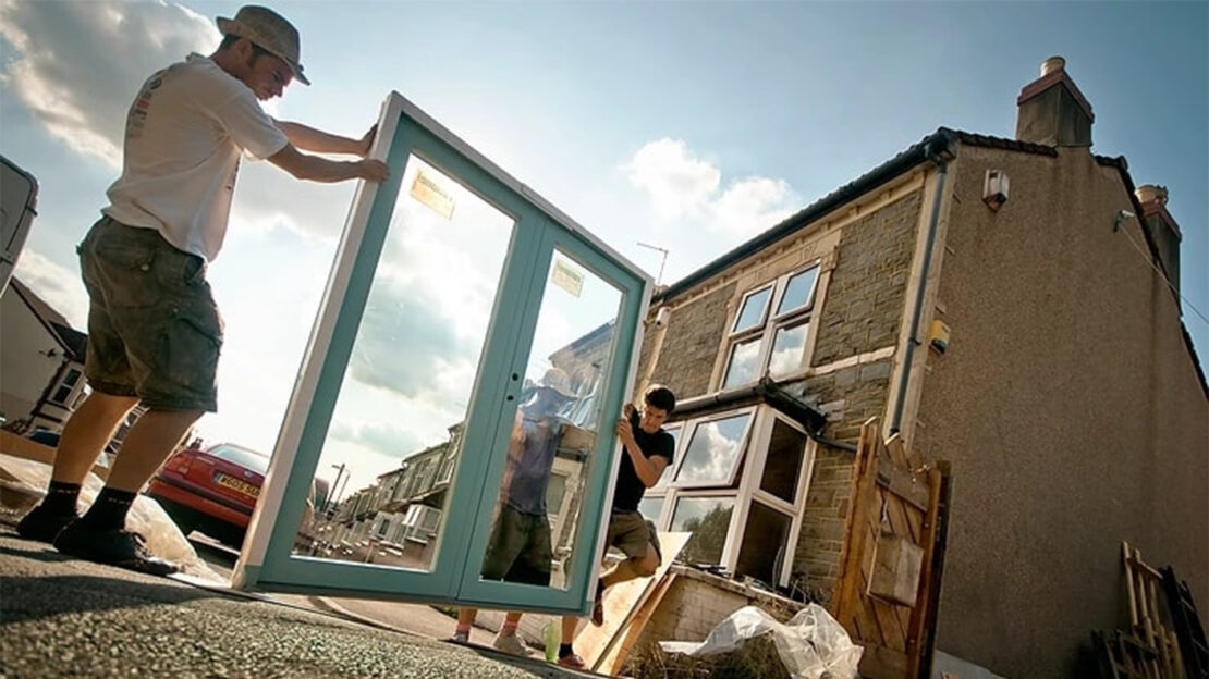 Three men holding a window frame