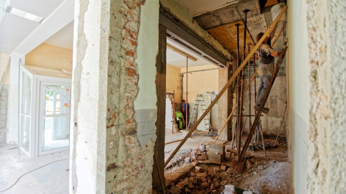 Photo showing renovation including bare walls and a man on a ladder